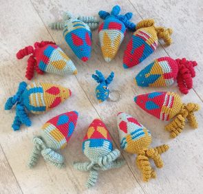 Kleurrijke gehaakte muizen in een cirkel, met rode, gele, roze en blauwe details op witte achtergrond.